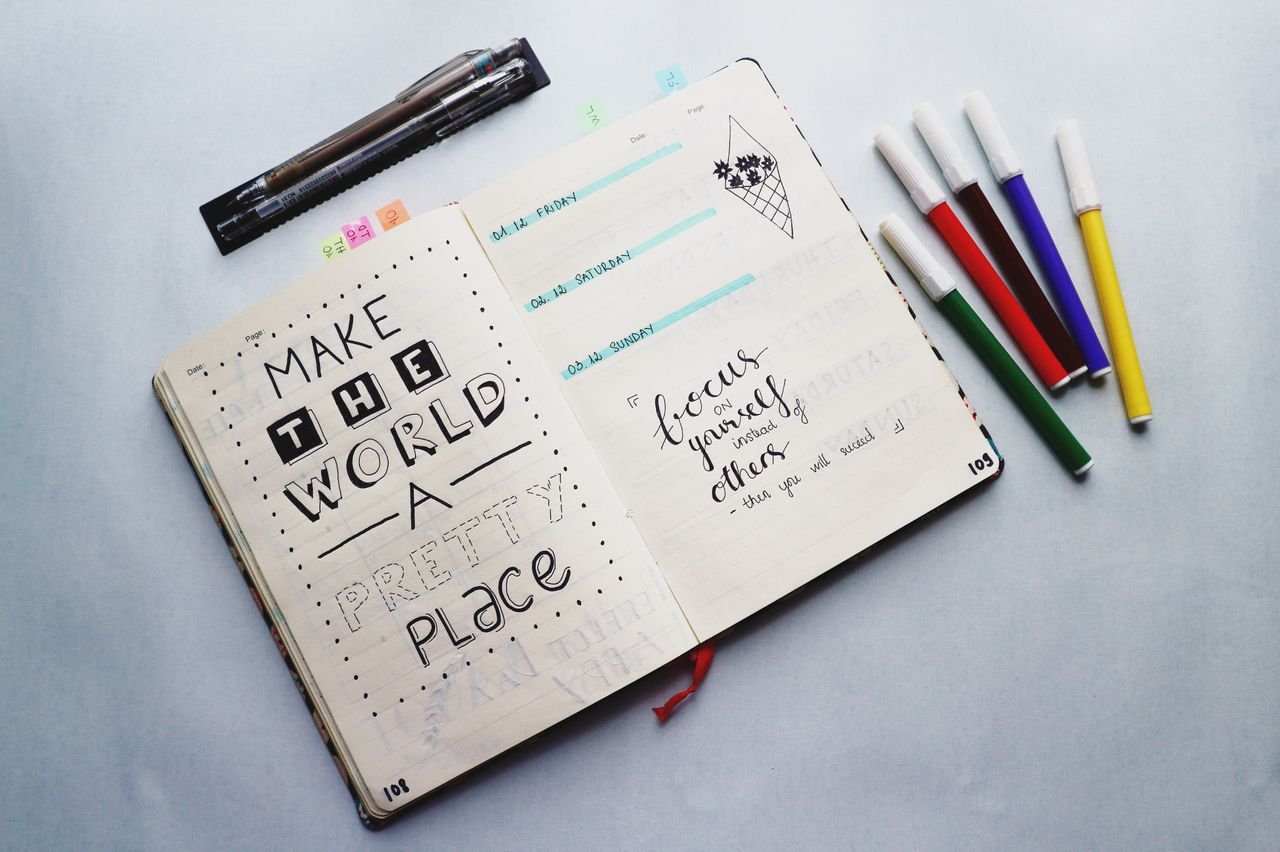 services-01 Open bullet journal with quotes and colorful markers for planning and creativity.